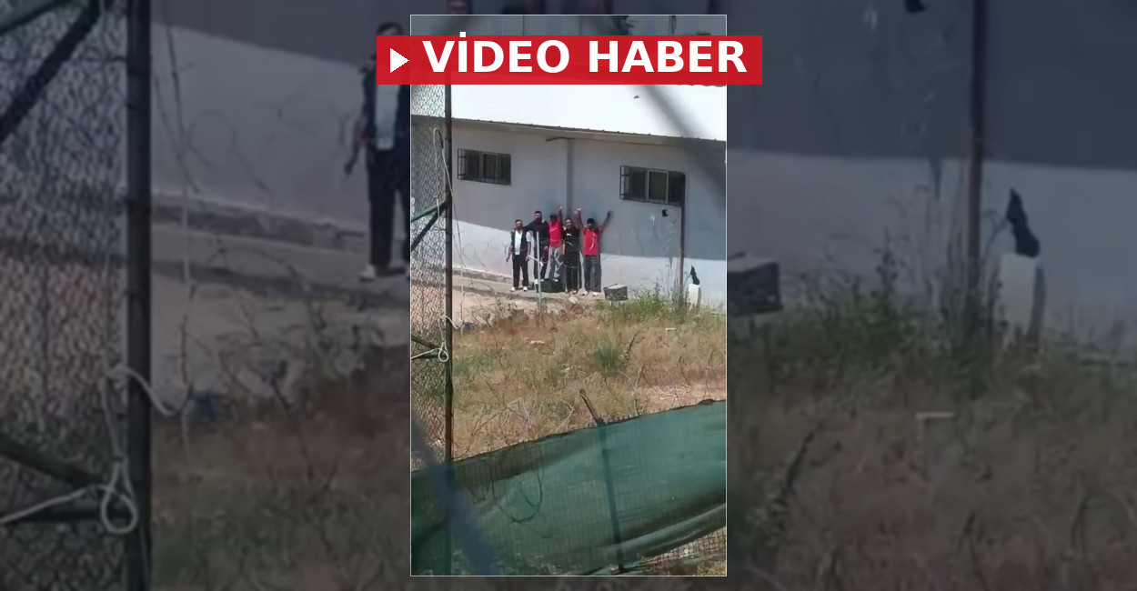 Balkonu cezaevine bakan bir kişi, cezaevi avlusunda volta atan mahkumları